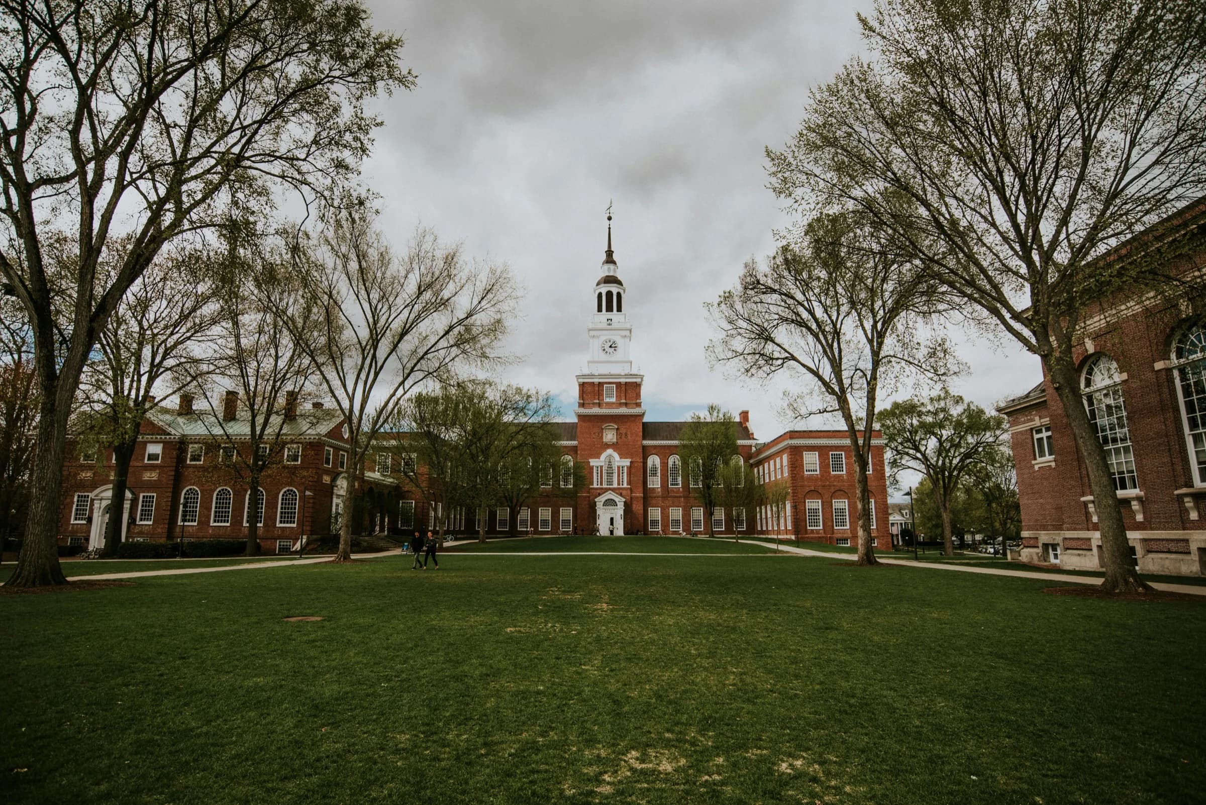 Historic red-brick campus and clock tower framed by mature trees.